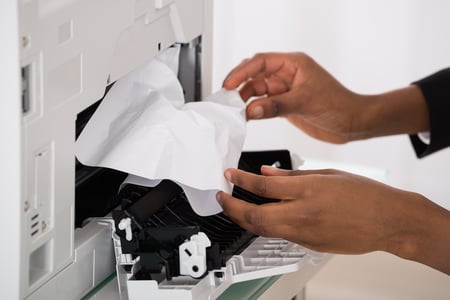 Zaglavljen papir - employee working with a paper jam from the copier machine